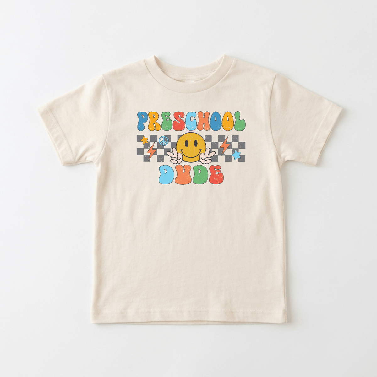 The Toodleroos Preschool Dude Kids Shirt – Back to School Tee is a beige shirt for preschoolers, showcasing “PRESCHOOL DUDE” in vibrant letters, a cheerful yellow smiley face with hands, and a bold black-and-white checkerboard backdrop—delivering the perfect retro kids tee style for your little one.