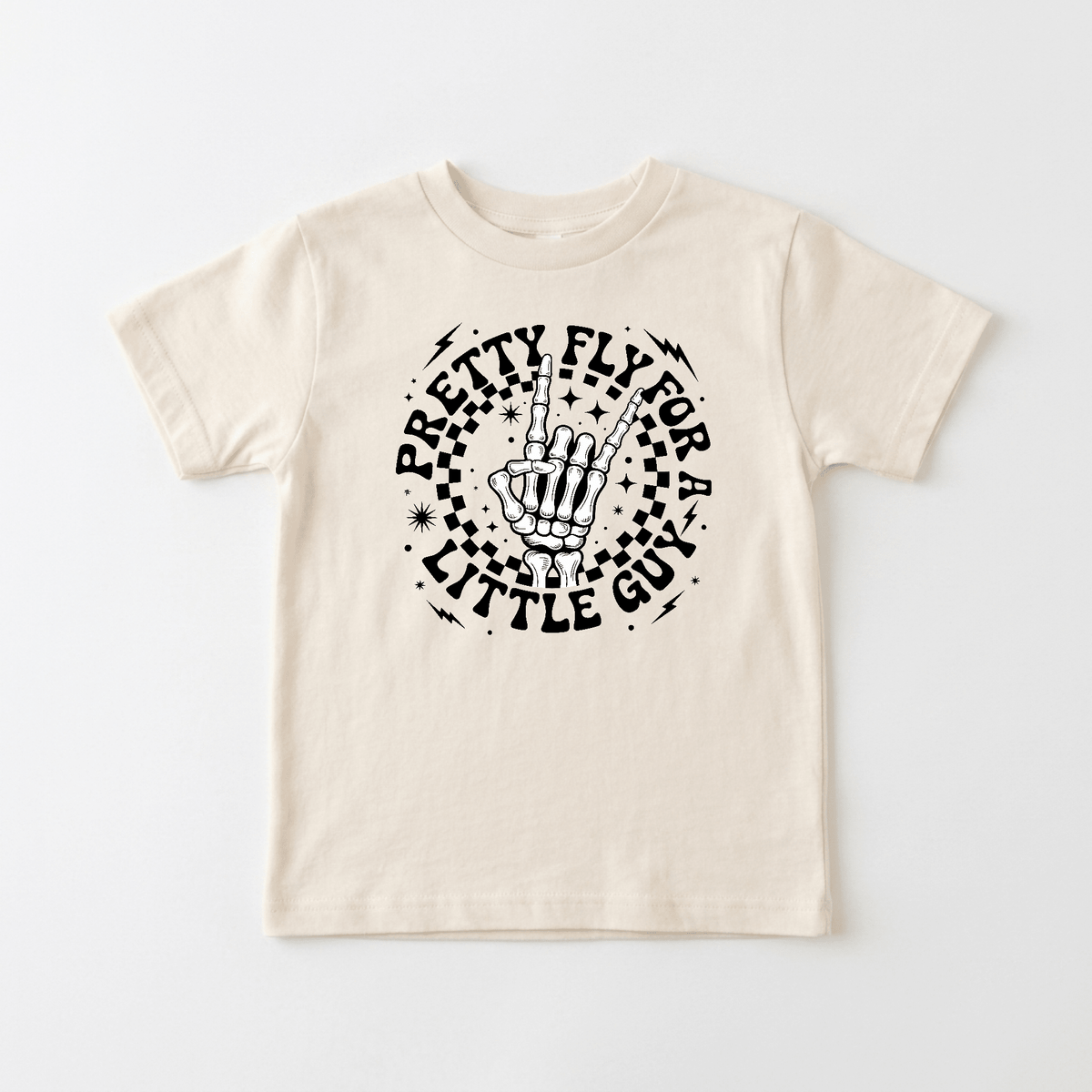 Outfit your little trendsetter in the Toodleroos Pretty Fly for a Little Guy Kids Shirt – Rock Skeleton Tee, a beige t-shirt featuring a black skeleton hand peace sign graphic surrounded by stars and retro lettering—perfect for cool kids who love standout style.