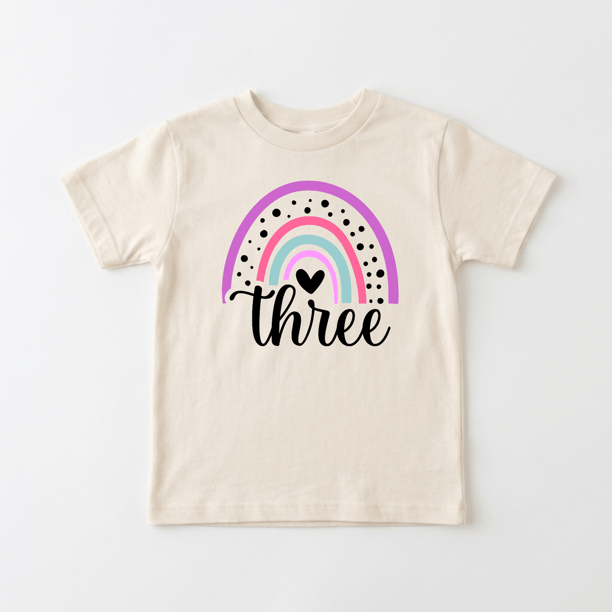 Celebrate your little one’s big day with the Toodleroos Rainbow Three Toddler Shirt – a beige 3rd birthday tee featuring a pastel rainbow with black dots and a heart above “three” in script font. This unique t-shirt is perfect as a rainbow toddler shirt for special occasions—explore more personalized kids shirts from Toodleroos!.