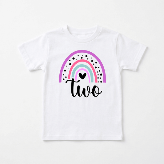 Celebrate your little one’s special day with the Rainbow Two Toddler Shirt – 2nd Birthday Tee by Toodleroos. Featuring a white background with a colorful rainbow, black dots, a small heart, and the word “two” elegantly written in black script beneath the design, this charming shirt is an adorable addition to any collection of personalized kids shirts or 2nd birthday shirts.