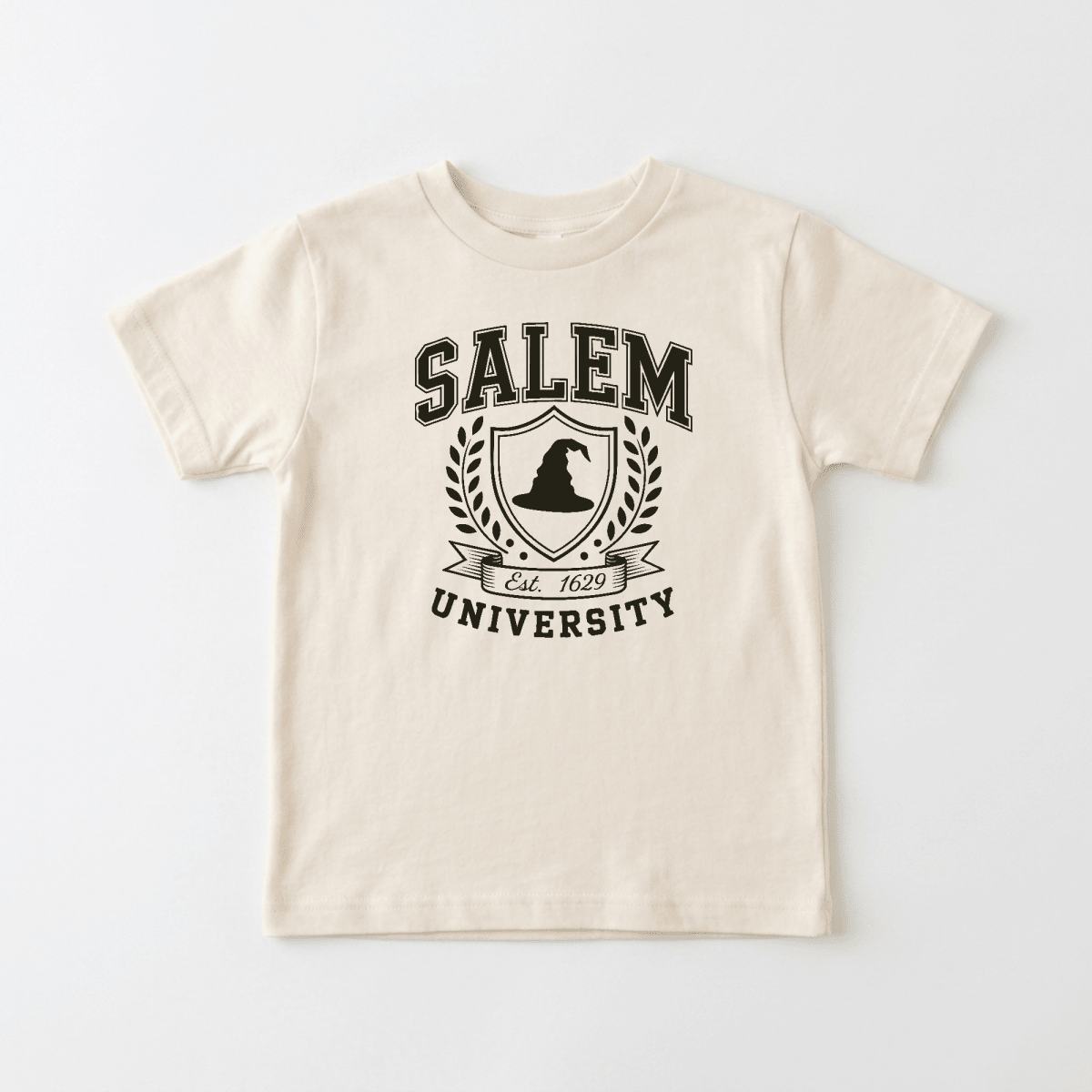 An off-white short-sleeve t-shirt with a black graphic print on the front reading 'SALEM UNIVERSITY' around a crest with a witch's hat and laurel wreath.
