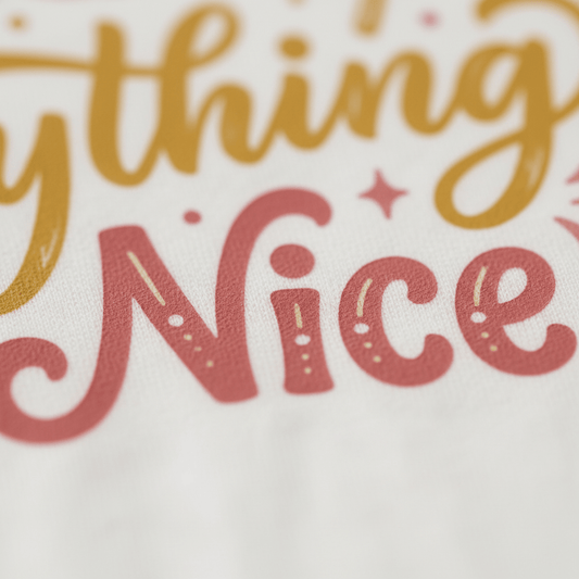 Close-up of colorful, cursive text on white fabric from the Sugar and Spice Toddler Girls Shirt – Lollipop Tee by Toodleroos. The design features the word “Nice” in pink with decorative dots and swirls, plus part of another word in yellow above it. Scattered pink dots and stars add a playful touch—perfect for any girls shirts collection.