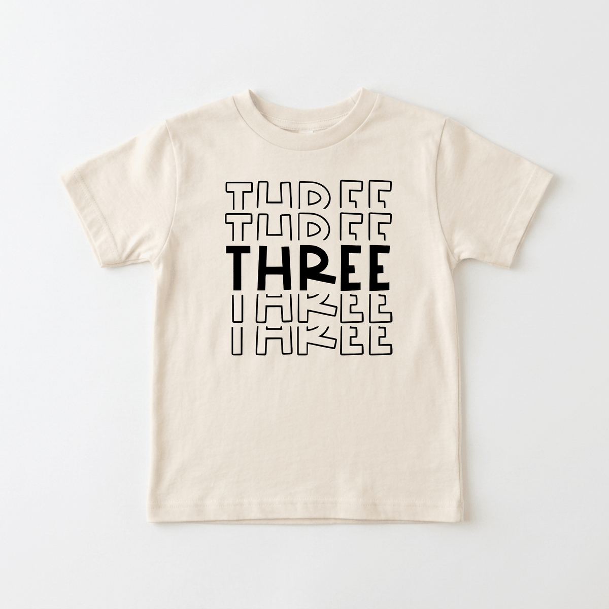 Celebrate your little one’s special day with the Toodleroos Three Birthday Toddler Shirt – 3rd Birthday Tee! This cream-colored, gender-neutral shirt features the word THREE printed three times in black, with a bold and solid middle THREE and outlined letters for the top and bottom, making it the perfect birthday tee for your toddler turning three.