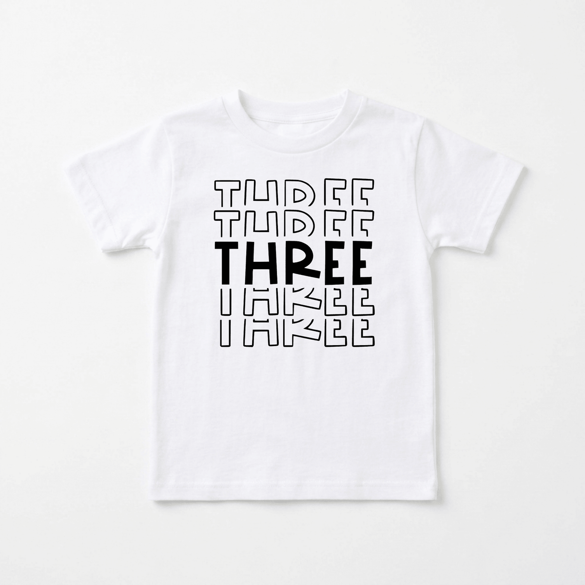 Introducing the “Three Birthday Toddler Shirt – 3rd Birthday Tee” from Toodleroos: This white T-shirt features the word THREE printed three times in black, each line increasing in boldness from top to bottom—with the middle THREE being extra bold and eye-catching. It’s the perfect, gender-neutral birthday shirt for your little one’s 3rd birthday celebration!.