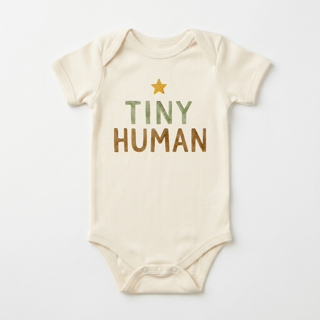 The Toodleroos Gender-Neutral Baby Onesie – Tiny Human Short-Sleeve Graphic Bodysuit showcases a cream-colored design with a yellow star and the phrase “TINY HUMAN” printed in green and brown lettering on the front, making it an ideal pick for fans of minimalist baby bodysuits and neutral baby clothing.