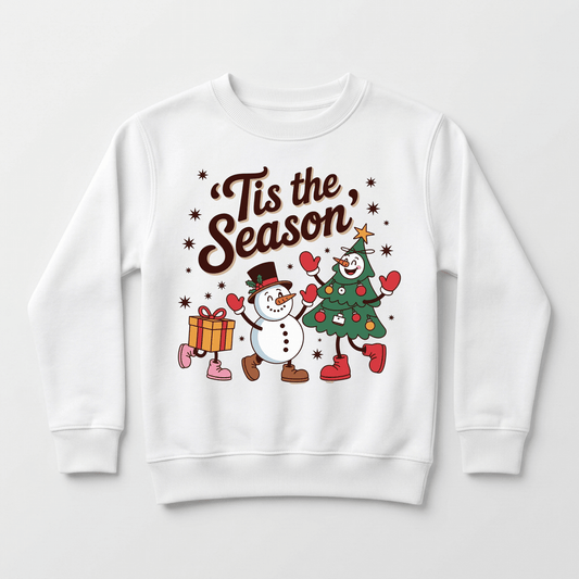 The Toodleroos ’Tis the Season Retro Christmas Toddler Sweatshirt features a cheerful design with a smiling snowman and a Christmas tree character holding hands, surrounded by snowflakes and a gift box—making it the perfect festive sweatshirt for toddler holiday celebrations.