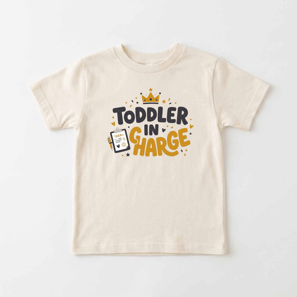 Introducing the Toodleroos Toddler in Charge Shirt – Funny Crown Tee: A beige unisex t-shirt featuring “Toddler in Charge” text, a crown graphic, scattered stars, and a juice box illustration labeled “Snack Boss.” This playful design adds fun to any wardrobe and is sure to stand out among funny kids shirts.