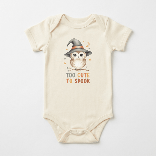 Dress your little one for their first Halloween with the Toodleroos Halloween Baby Onesie – Too Cute to Spook Owl Short-Sleeve Bodysuit, featuring a beige design with an adorable owl in a witch hat perched on a branch and “Too Cute To Spook” printed below—a charming choice for any baby who loves owls.