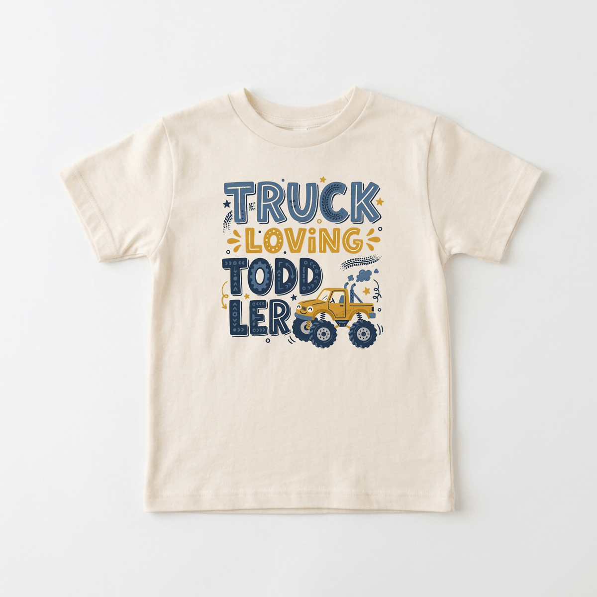 The Toodleroos Truck Loving Toddler Boys Shirt – Monster Truck Tee is a cream-colored t-shirt featuring the phrase “Truck Loving Toddler” in blue and yellow, a playful cartoon yellow truck, and decorative stars and dots—making it an ideal addition to boys shirt collections or as a fun monster truck shirt for your little one.