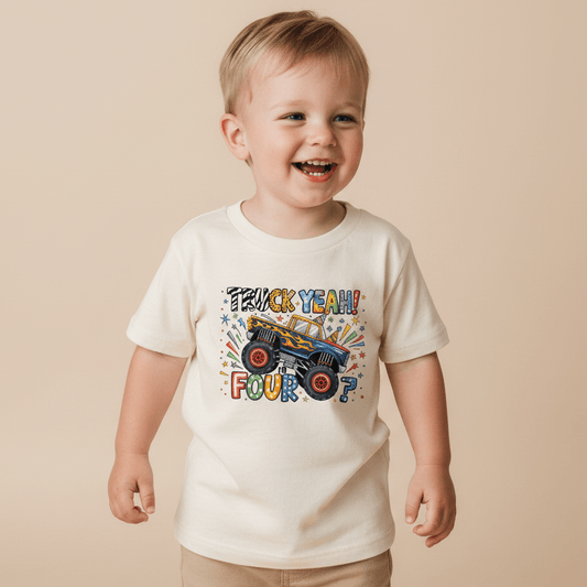 A smiling young child wears the Toodleroos “Truck Yeah I’m Four” Toddler Shirt—a cream-colored Monster Truck 4th Birthday Tee featuring vibrant graphics and playful “Truck Yeah! Four?” text on the front.