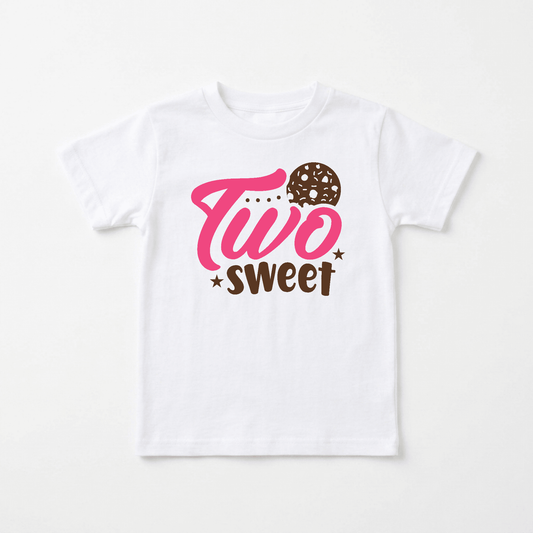 Celebrate your little one’s second birthday with the Toodleroos Two Sweet Toddler Shirt – Cookie 2nd Birthday Tee. This adorable white shirt features “Two” in pink letters with a donut-shaped “o,” and “sweet” in brown below, surrounded by small stars—making it the perfect Two Sweet toddler shirt for their special day.