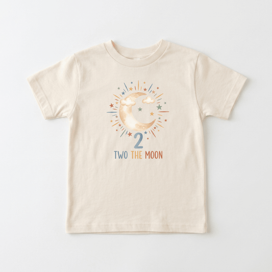 Dress your little one in the perfect 2nd birthday outfit with this cream-colored “2nd Birthday Toddler Shirt – Two the Moon Celestial Short-Sleeve Tee” by Toodleroos. It features a cheerful crescent moon and clouds surrounded by colorful stars, the number 2 underneath, and the fun phrase “TWO THE MOON” in multicolored letters—making it an ideal shirt for your toddler’s special day.