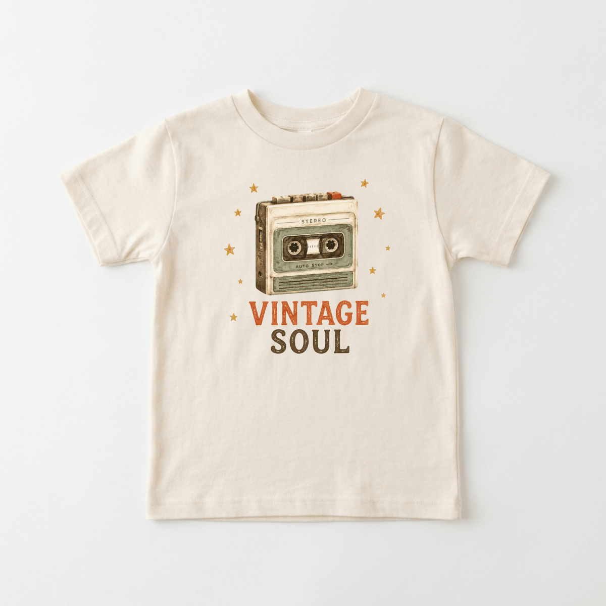 The Toodleroos Toddler Music Shirt – Vintage Soul Retro Cassette Short-Sleeve Tee is a beige t-shirt with an illustration of a cassette tape surrounded by orange stars and “VINTAGE SOUL” printed below in orange and gray letters, making it the perfect shirt for music-loving toddlers with vintage style.