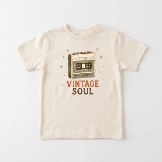 The Toodleroos Toddler Music Shirt – Vintage Soul Retro Cassette Short-Sleeve Tee is a beige t-shirt with an illustration of a cassette tape surrounded by orange stars and “VINTAGE SOUL” printed below in orange and gray letters, making it the perfect shirt for music-loving toddlers with vintage style.