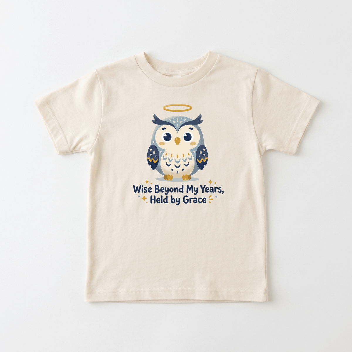 The Wise Beyond My Years Owl Kids Shirt – Faith Tee by Toodleroos is a cream-colored children’s T-shirt featuring a cartoon owl with a halo above its head and the phrase “Wise Beyond My Years, Held by Grace” printed below in blue and gold letters. This faith-inspired shirt for kids combines playful style with meaningful Christian messaging, perfect for little ones.