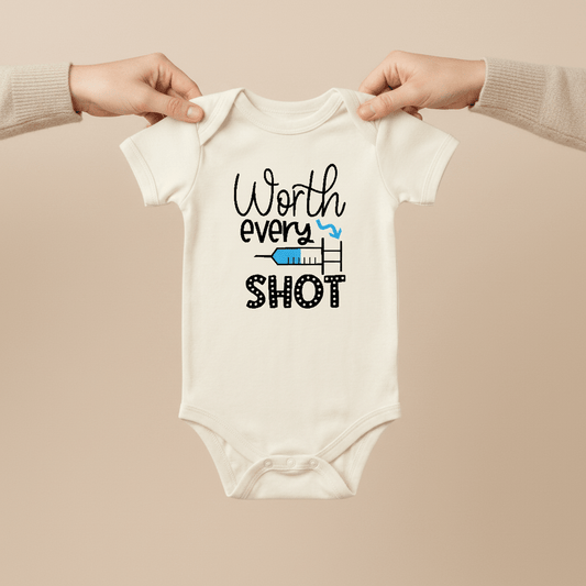 Two hands hold a white Worth Every Shot Baby Onesie – IVF Journey Bodysuit by Toodleroos. The onesie features the words “Worth every shot” alongside a small illustration of a syringe and heart, symbolizing IVF or fertility treatments. This meaningful baby bodysuit from Toodleroos makes an ideal gift for those on their fertility journey or serves as a touching baby announcement outfit, celebrating hope and resilience.